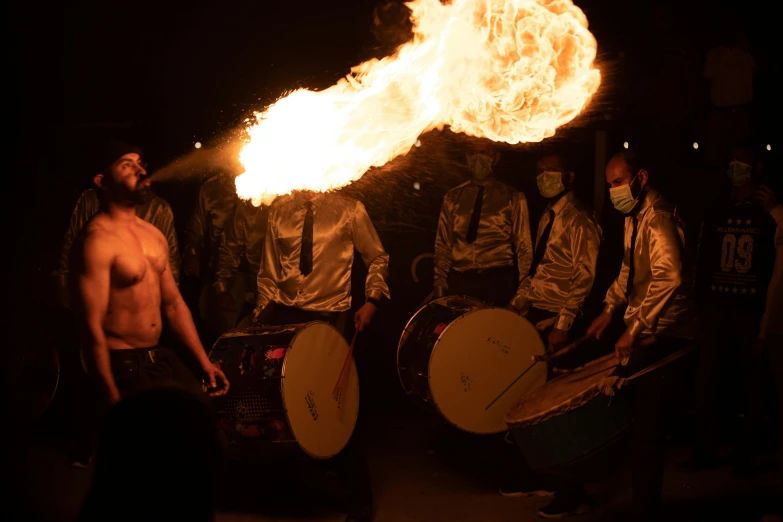 a group of men standing next to each other in front of a fire, pexels contest winner, gutai group, playing drums, kitsune holding torch, avatar image, muzzle flash