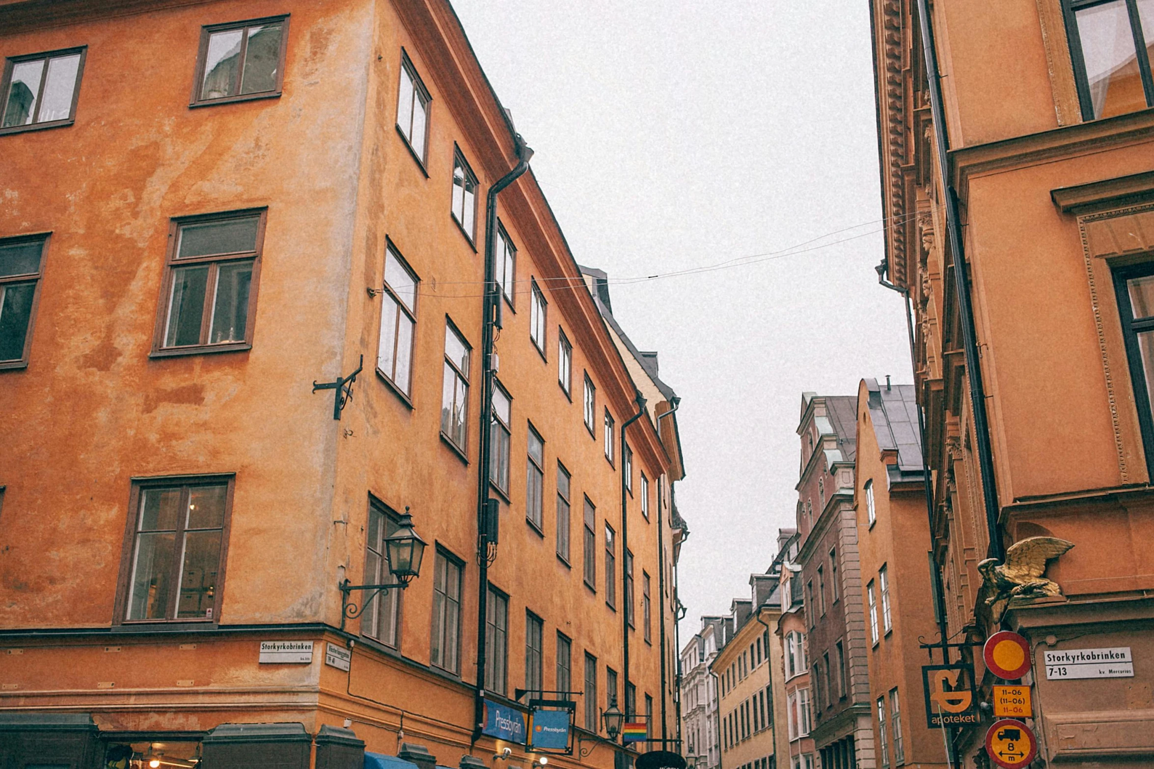 a group of people walking down a street next to tall buildings, by Christen Dalsgaard, pexels contest winner, neoclassicism, swedish house, yellowed with age, 🦩🪐🐞👩🏻🦳, cobblestone streets