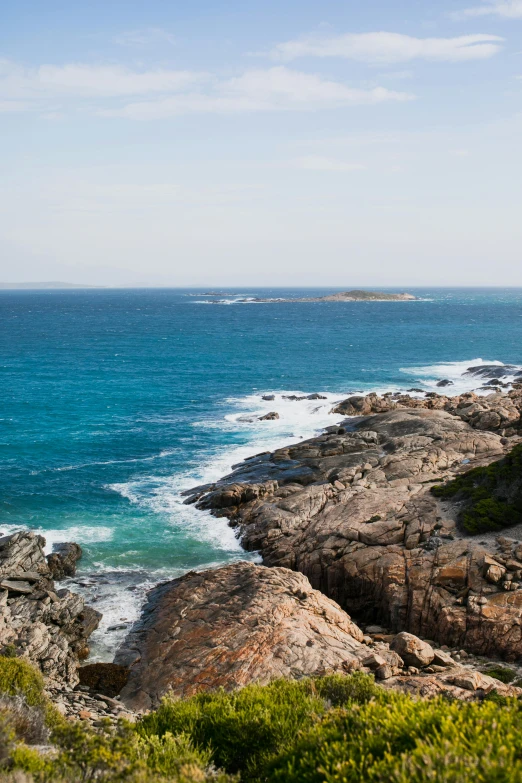 a man standing on top of a cliff next to the ocean, by Elizabeth Durack, slide show, granite, overview, distant photo