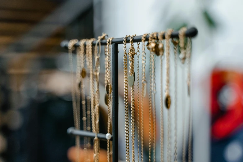 a rack filled with lots of different types of necklaces, a photo, trending on pexels, gold raining in the background, stanchions, exterior shot, gold and black metal