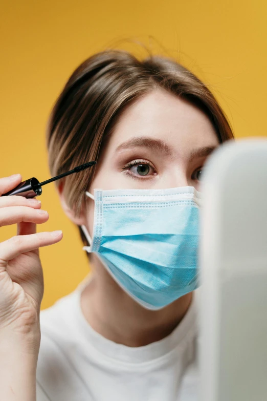 a woman putting on mascara in front of a computer, a picture, trending on pexels, masked doctors, holding a yellow toothbrush, thumbnail, profile pic