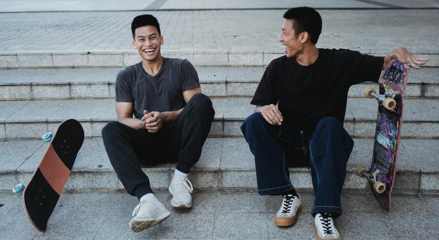 two men sitting on the steps with their skateboards, inspired by Wang Duo, pexels contest winner, smiling laughing, asian human, wearing cargo pants, avatar image