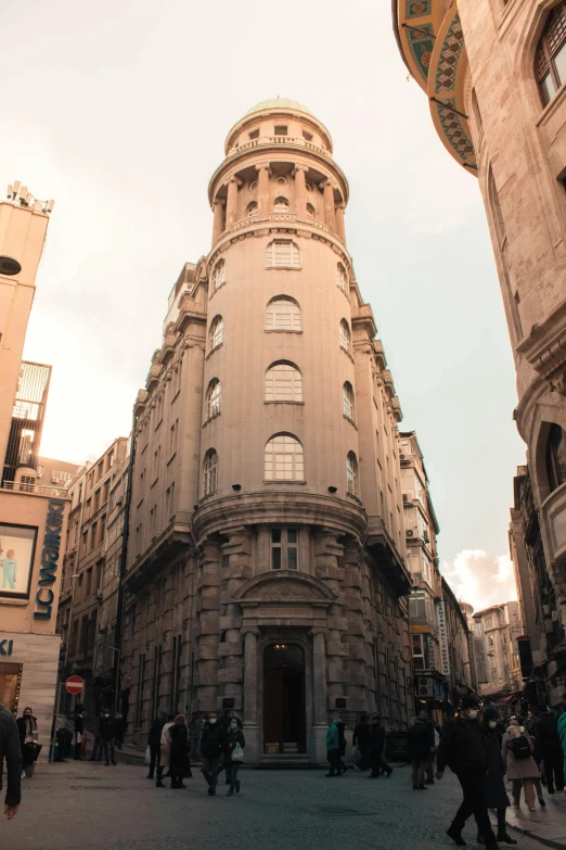 a group of people walking down a street next to tall buildings, by Gaudi, unsplash, art nouveau, wizard's tower, buenos aires, exterior view, spherical