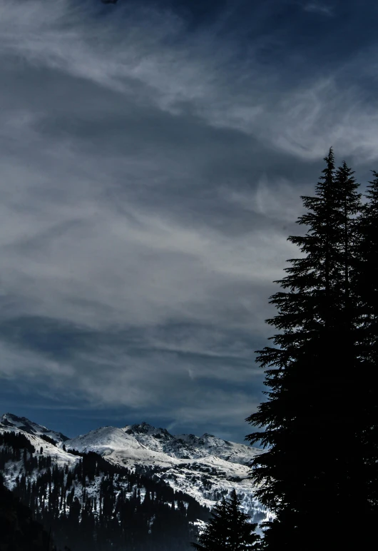 a man flying through the air while riding a snowboard, unsplash, les nabis, strange trees and clouds, whistler, dark clouds in the sky, today\'s featured photograph 4k