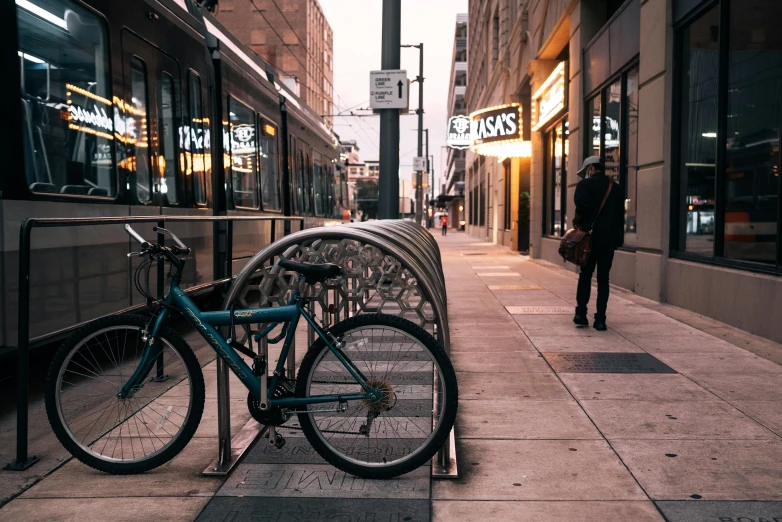 a bicycle parked next to a bike rack on a sidewalk, by Carey Morris, pexels contest winner, city street at dusk, street of teal stone, minneapolis, storefronts