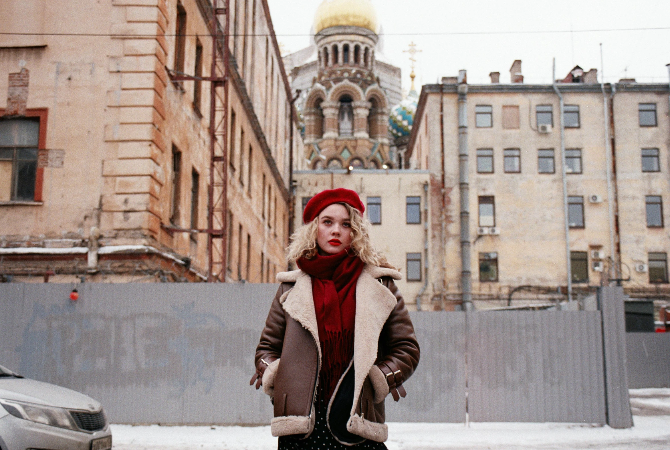 a woman standing in the middle of a snowy street, an album cover, by Julia Pishtar, pexels contest winner, socialist realism, russian temple, brown leather jacket, gold and red, portrait featured on unsplash