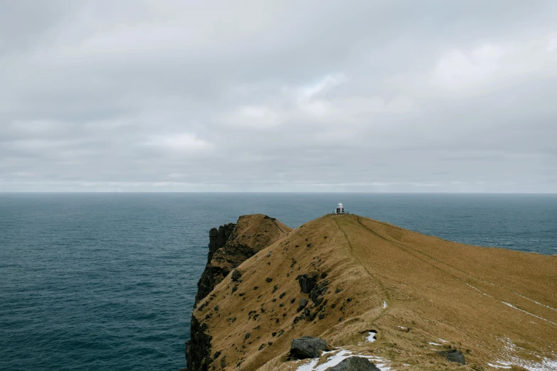 a man standing on top of a mountain next to the ocean, by Matthias Stom, pexels contest winner, slight overcast weather, thumbnail, eeyrie, high quality photo