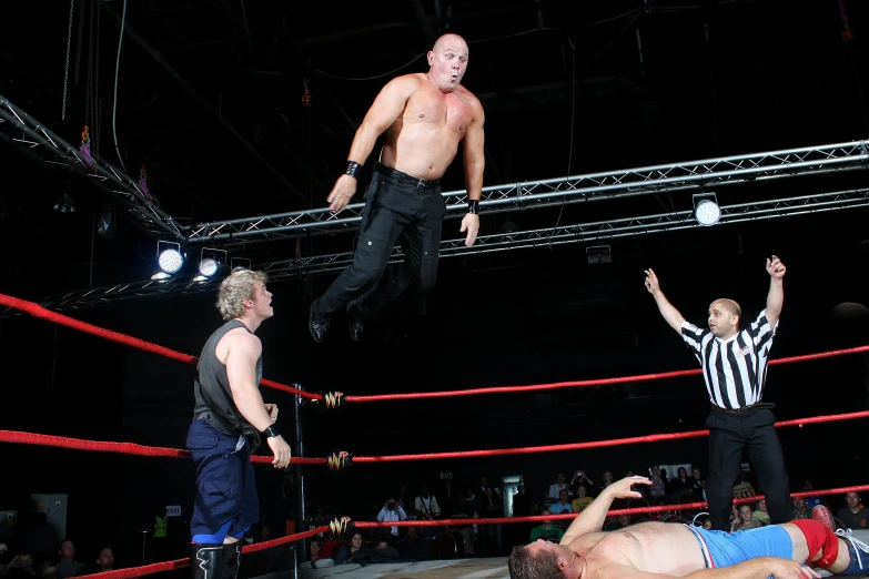 a group of men standing on top of a wrestling ring, greg broadmore, floating in the air, profile image, black and reddis