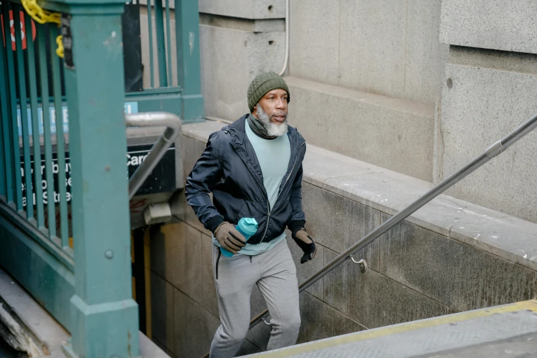 a man walking down a set of stairs, a photo, wearing teal beanie, morgan freeman, 8k photo, nyc