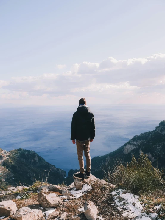 a person standing on top of a mountain, trending on pexels, capri coast, looking off into the distance, wondering about others, high quality image”