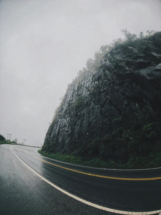 a curve in the road with a mountain in the background, unsplash contest winner, visual art, heavy rainy, cliff side, gopro footage, ( ( ( ( kauai ) ) ) )