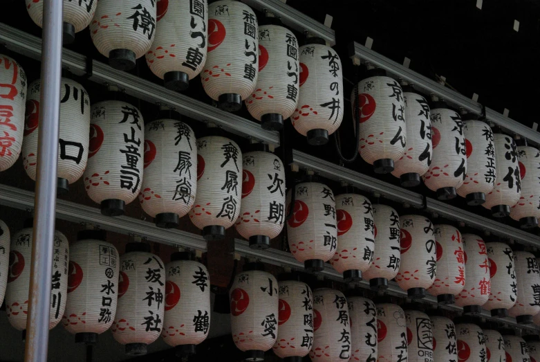 a wall filled with lots of white and red paper lanterns, a picture, inspired by Sesshū Tōyō, sōsaku hanga, large jars on shelves, with names, teaser, photograph