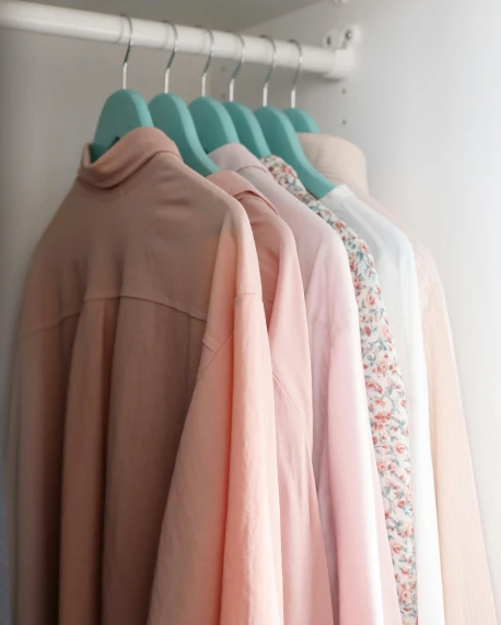 clothes hanging on a rack in a closet, by Alice Mason, trending on unsplash, pastel pink robes, wearing a light blue shirt, green and pink colour palette, wearing a light shirt