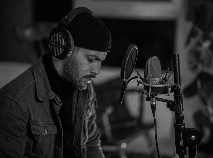 a man with headphones sitting in front of a microphone, an album cover, by Ejnar Nielsen, taken with sony alpha 9, reza afshar, singing into microphone, cory loftis