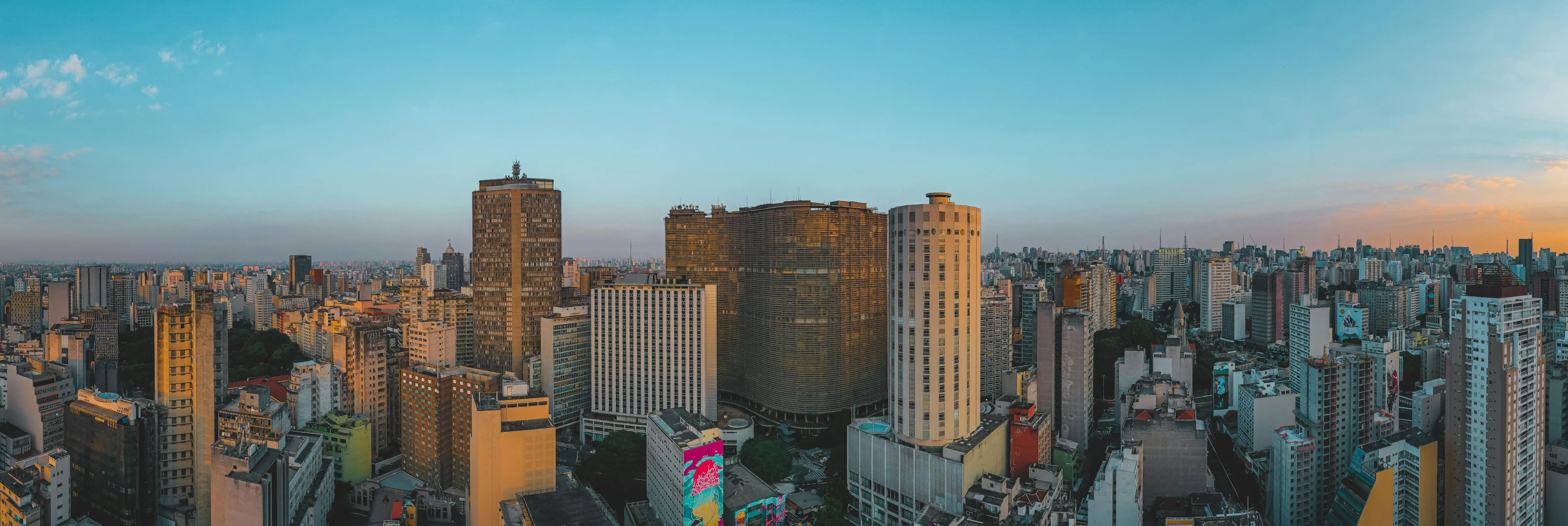 a view of a city from the top of a building, by Xavier Blum Pinto, pexels contest winner, brutalism, avenida paulista, panoramic widescreen view, golden hour photo, aerial view cinestill 800t 18mm