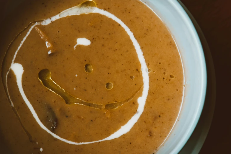 a bowl of soup with a smiley face drawn on it, an album cover, by Lee Loughridge, unsplash, renaissance, chocolate sauce, close-up from above, brown gravy, ignant