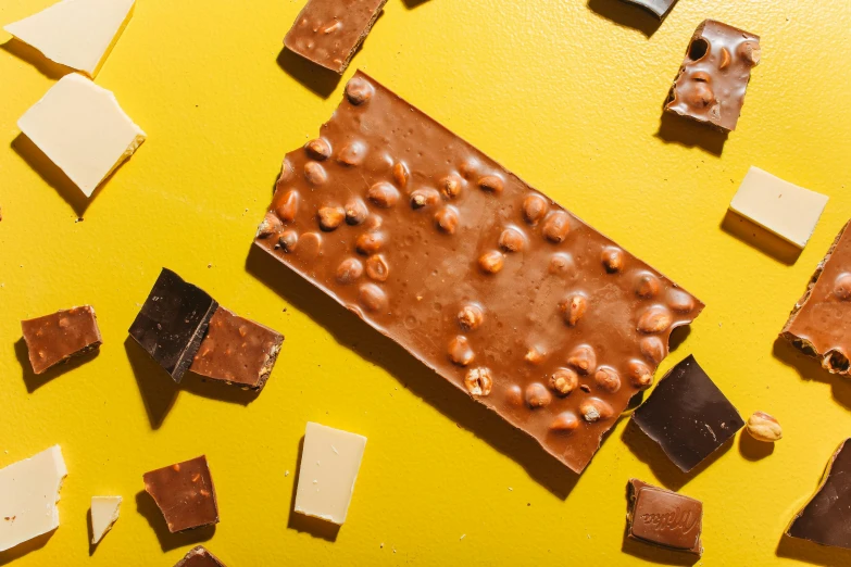 a close up of pieces of chocolate on a yellow surface, by Julia Pishtar, trending on pexels, bauhaus, made of baked beans, rectangle, 2 1 0 mm, knolling