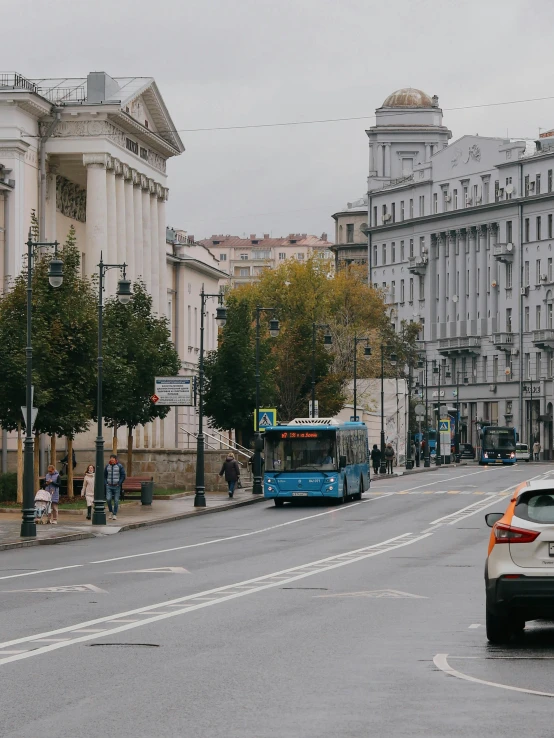 a car driving down a street next to tall buildings, by Emma Andijewska, pexels contest winner, socialist realism, lviv historic centre, public bus, 🚿🗝📝, russian neoclassicism