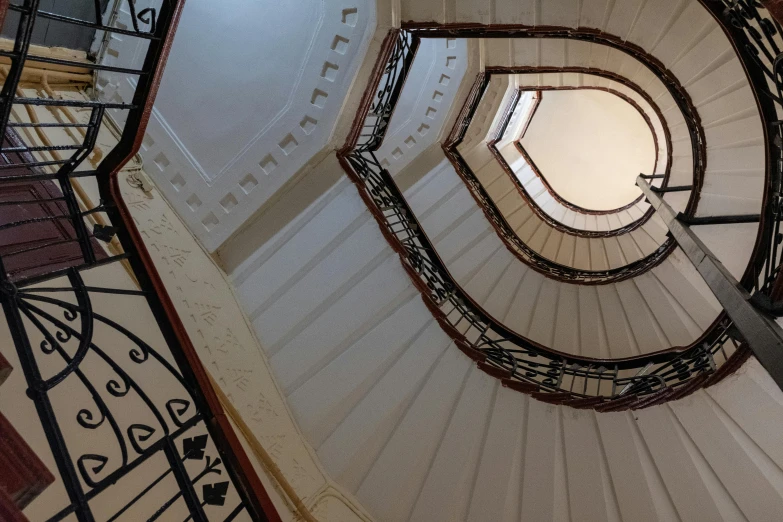 a spiral staircase in a building with a skylight, an album cover, by Konrad Witz, unsplash contest winner, art nouveau, kalighat, ignant, wide grand staircase, view from ground level