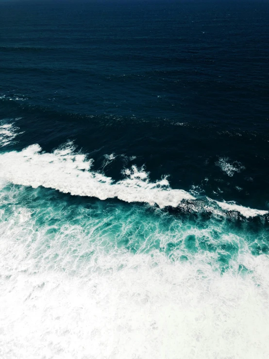 a large body of water next to a beach, pexels contest winner, cresting waves and seafoam, looking down on the camera, deep blue ocean color, today\'s featured photograph 4k