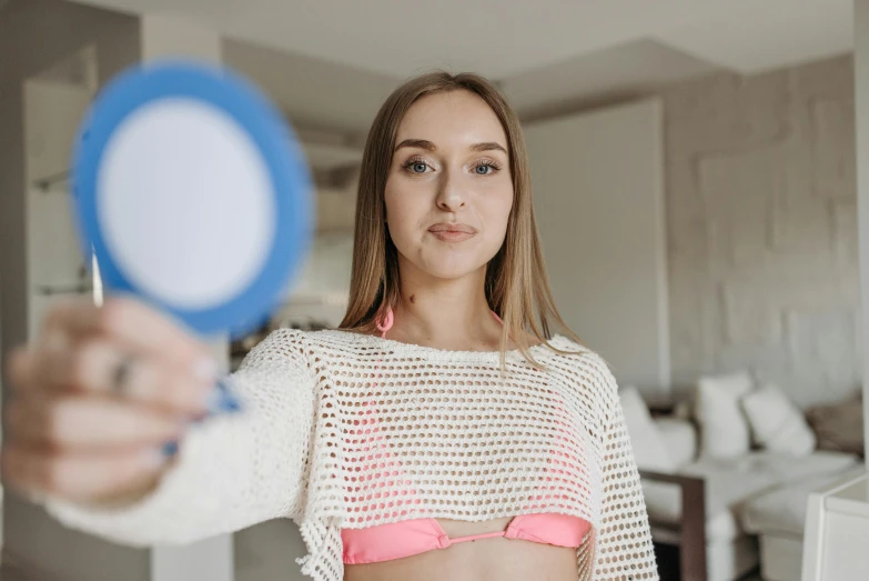 a woman in a bikini holding a mirror, a colorized photo, by Emma Andijewska, pexels contest winner, avatar image, wearing a cute top, doctors mirror, sydney sweeney