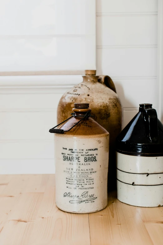 a couple of jars sitting on top of a wooden table, a still life, unsplash, large black kettle on hearth, white background, portrait n - 9, round bottle