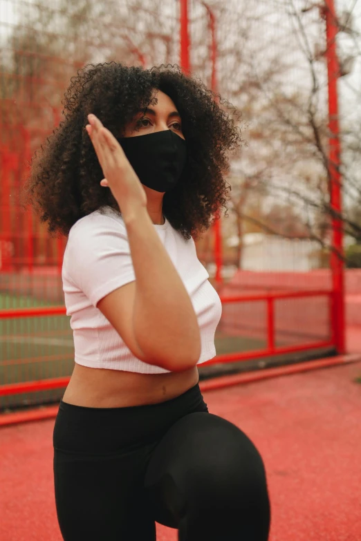 a woman in black leggings and a black face mask, by Carey Morris, trending on pexels, red sport clothing, curls, hear no evil, university