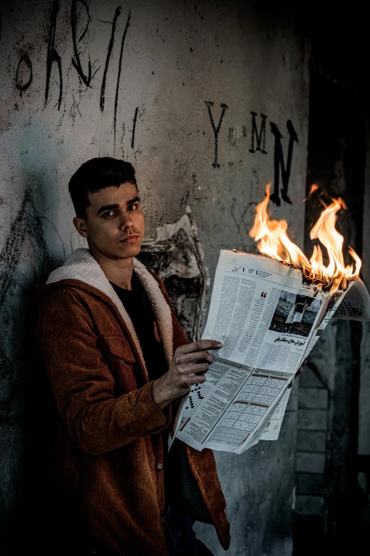 a man holding a newspaper in front of a fire, an album cover, pexels contest winner, young spanish man, high quality photo, dark backdrop, burned city