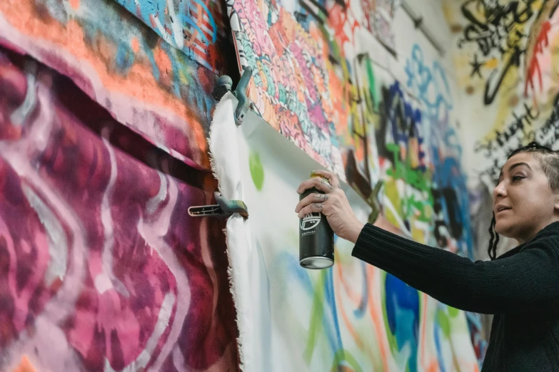 a woman spray painting graffiti on a wall, inspired by James Rosenquist, trending on unsplash, action painting, fabric, studio photo, on artstastion, mid shot photo