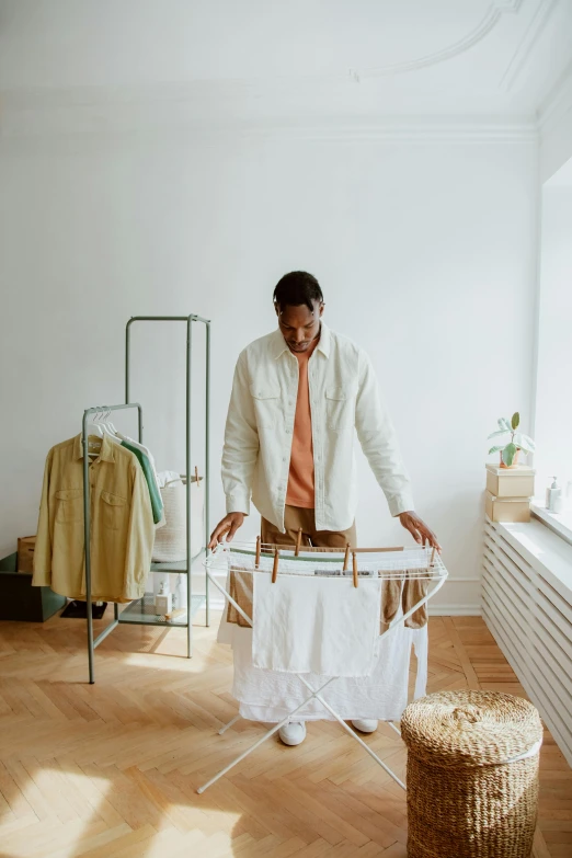 a man ironing clothes on a clothes rack, pexels contest winner, renaissance, brown and cream color scheme, in a white room, collection product, centered design