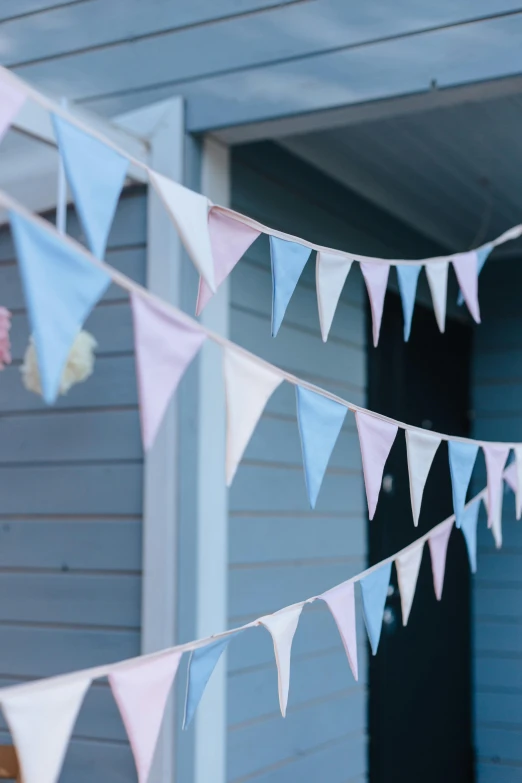 a group of bunting flags hanging from the side of a house, by Helen Stevenson, unsplash, pastel blues and pinks, detail shot, made of glazed, softly lit