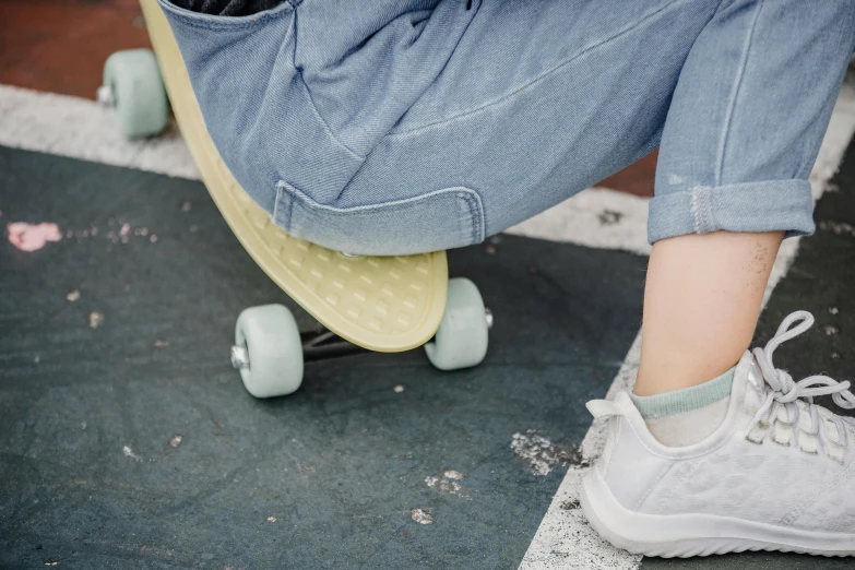 a close up of a person on a skateboard, trending on pexels, pastel green, woman is sitting, blue jeans and grey sneakers, sustainable materials