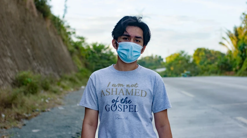 a man wearing a face mask and holding a skateboard, unsplash, biblical clothing, avatar image, wearing a light blue shirt, south east asian with round face