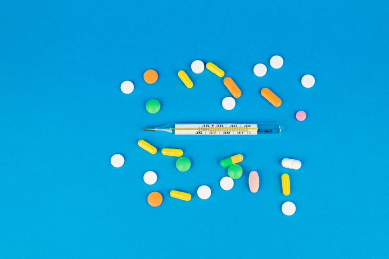 pills and a thermometer on a blue background, inspired by Damien Hirst, visual art, some orange and blue, background image, blue ballpoint pen, product design shot