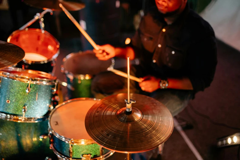 a man sitting in front of a drum set, pexels contest winner, copper and deep teal mood, lots of cymbals, 3 jazz musicians, bottom angle