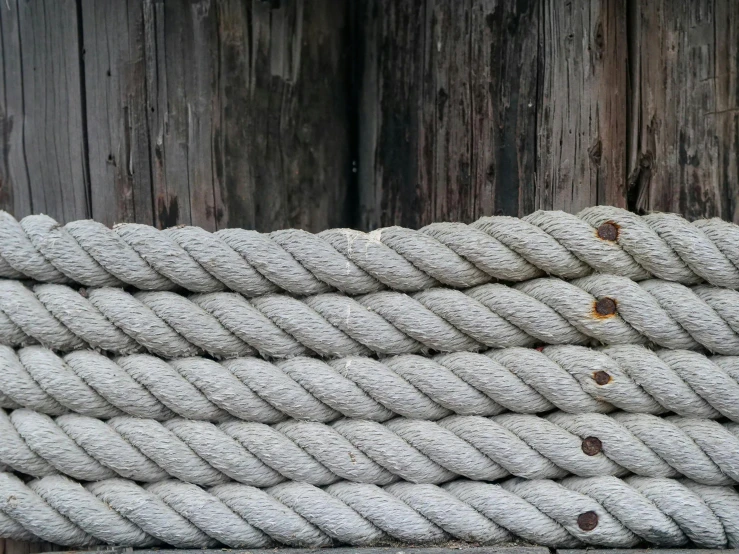 a close up of a rope on a wooden fence, trending on pexels, silver，ivory, background image, stacked image, ground - level medium shot