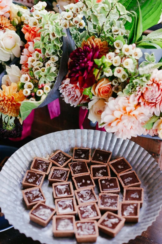 a close up of a plate of food near flowers, chocolate candy bar packaging, chocolate frosting, bay area, bouquets