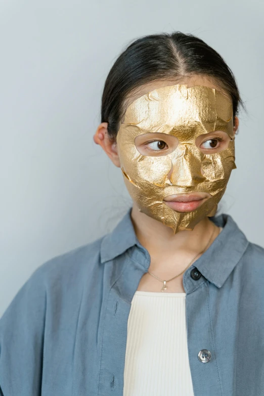 a woman with a gold mask on her face, by Ellen Gallagher, trending on pexels, young adorable korean face, face and body clearly visible, cardboard, bark for skin