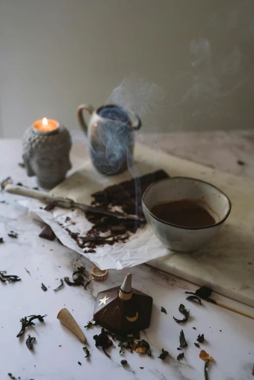 a tea pot sitting on top of a table next to a cup of tea, a still life, process art, waxy candles, smothered in melted chocolate, wabi - sabi, product display photograph
