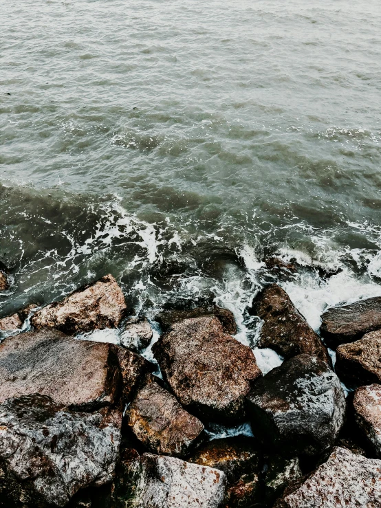 a group of rocks sitting on top of a body of water, happening, rough water, trending on vsco, hq 8k cinematic, multiple stories