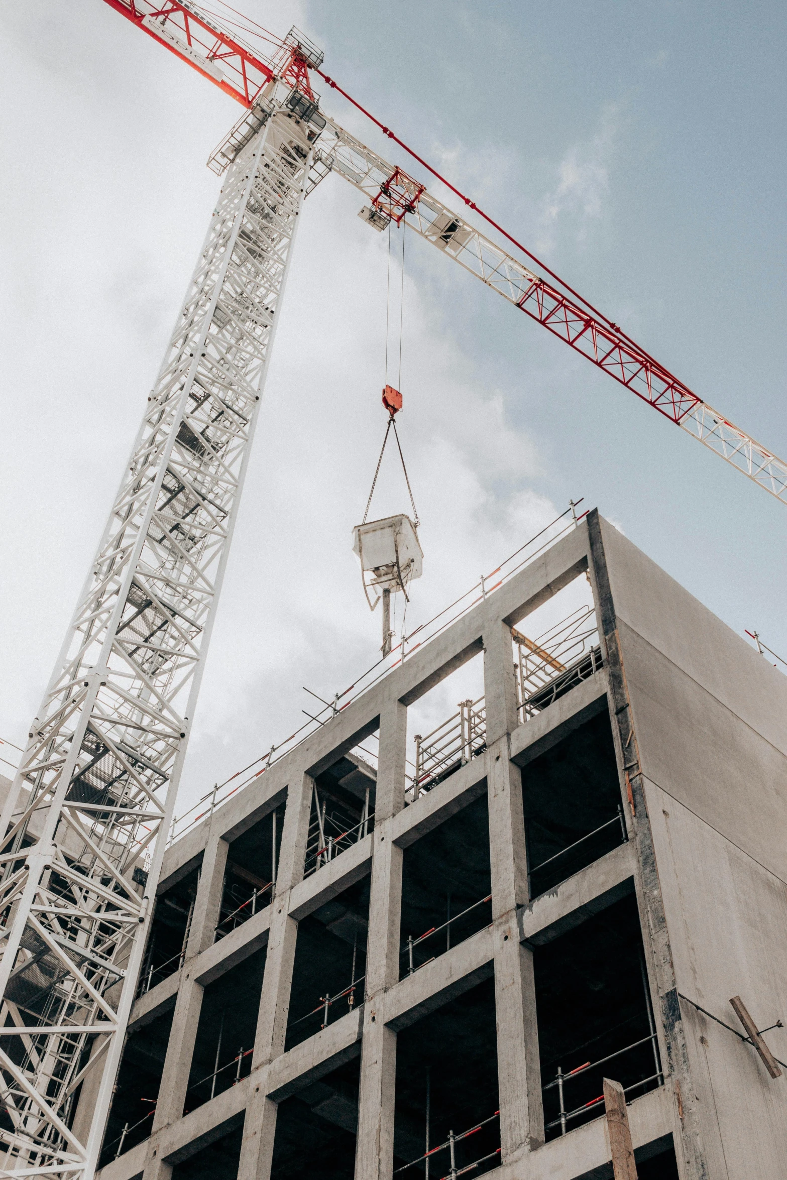 a crane standing on top of a building next to a tall building, concrete building, lynn skordal, modular, thumbnail