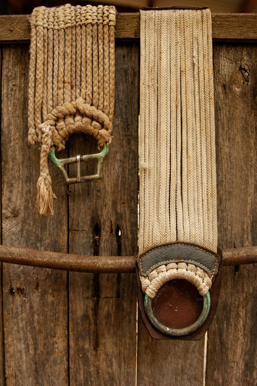 a pair of belts hanging on the side of a wooden fence, by Peter Churcher, laos, slide show, half horse, hemp