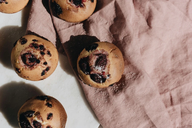 a bunch of muffins sitting on top of a pink cloth, a photo, by Emma Andijewska, trending on pexels, mingei, berries inside structure, steamed buns, thumbnail, background image