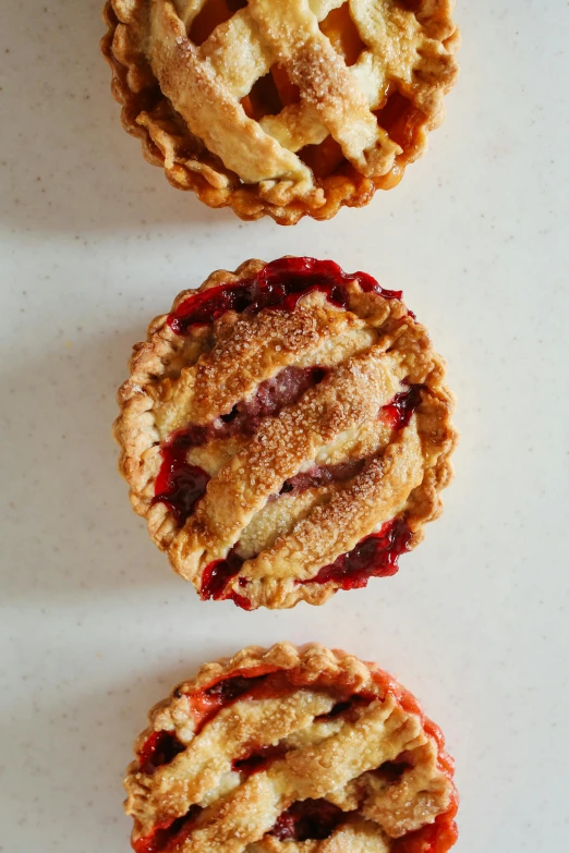 three mini pies sitting on top of a table, raspberry banana color, 3 - piece, lined up horizontally, handcrafted