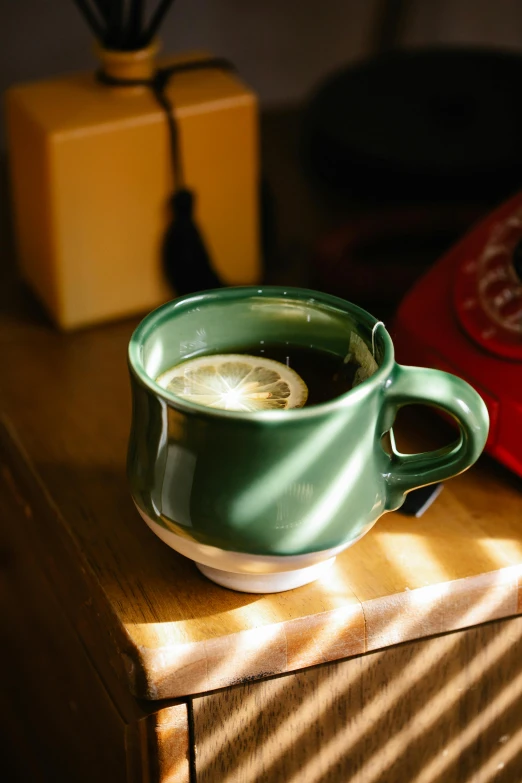 a cup of coffee sitting on top of a wooden table, dark green, lemon, f / 2 0, fan favorite