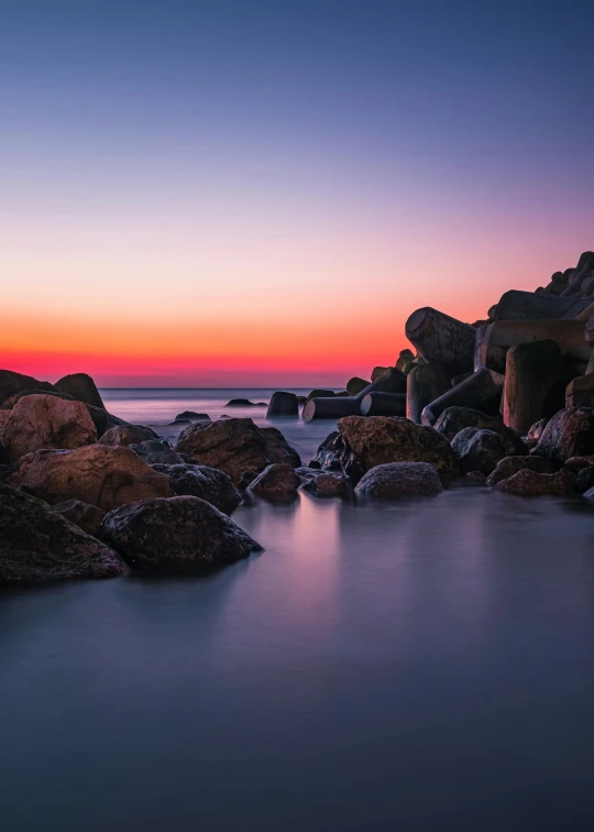 a large body of water surrounded by rocks, a picture, unsplash contest winner, romanticism, pastel sunset, south african coast, ultrawide lens”, fujifilm”