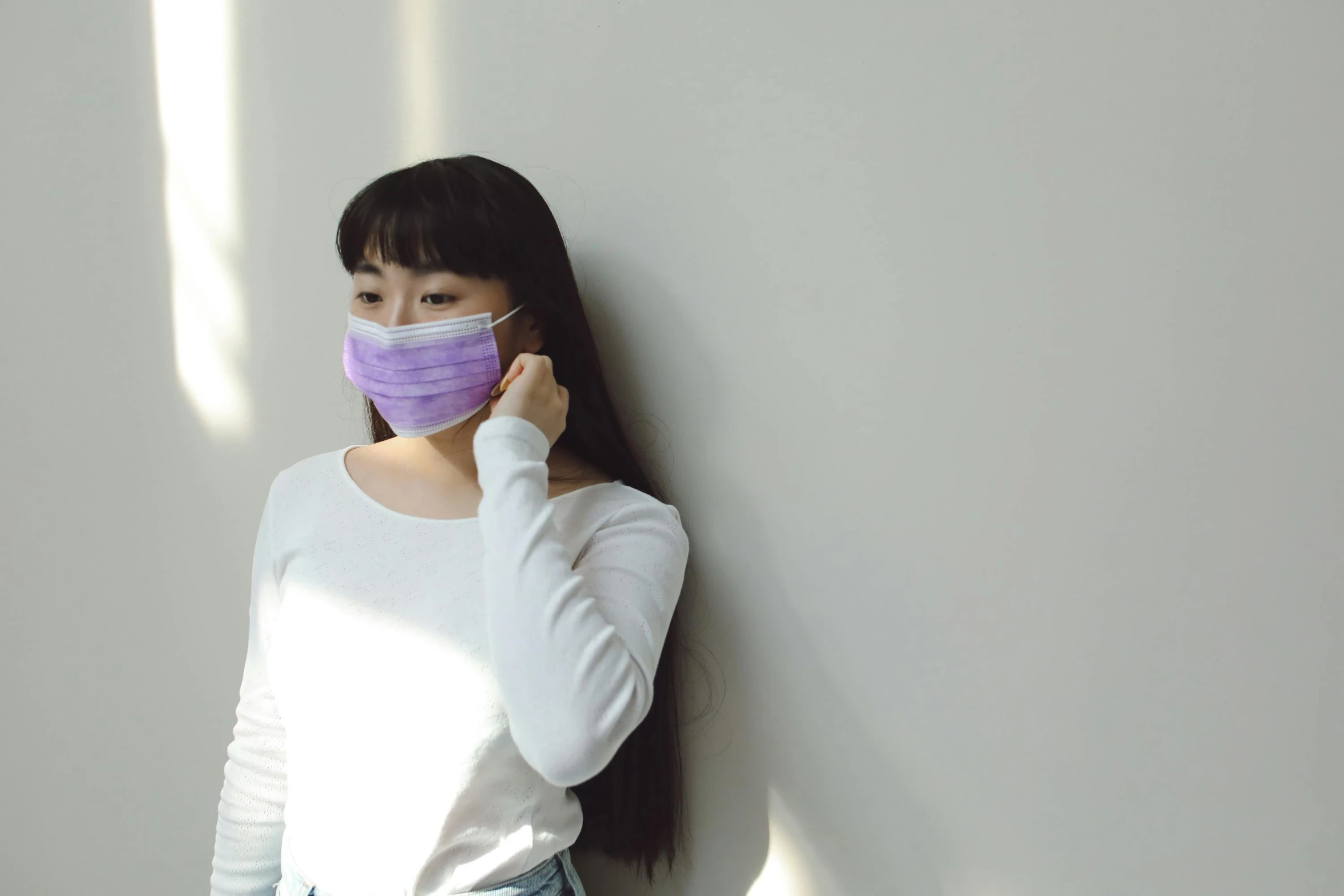 a woman wearing a face mask leaning against a wall, trending on pexels, white and purple, korean girl, avatar image, medical