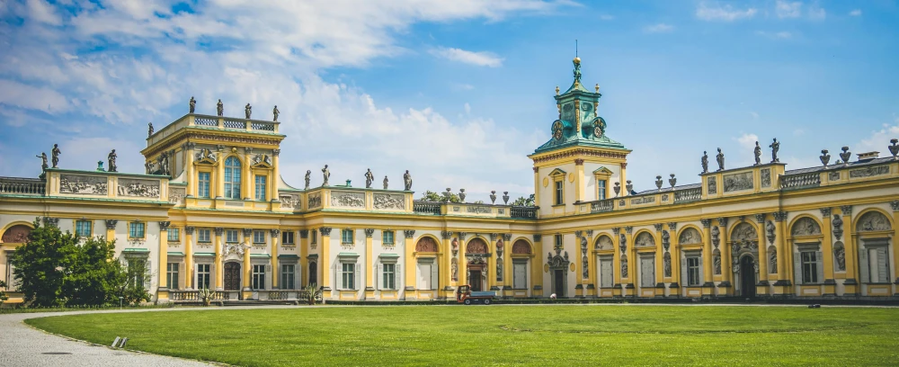 a large building with a clock tower on top of it, by Jan Stanisławski, pexels contest winner, rococo, lawn, yellow and green scheme, panoramic, colonnade