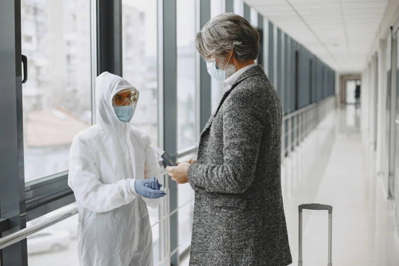 a couple of people standing next to a window, white coat, technical suit, covid, airport