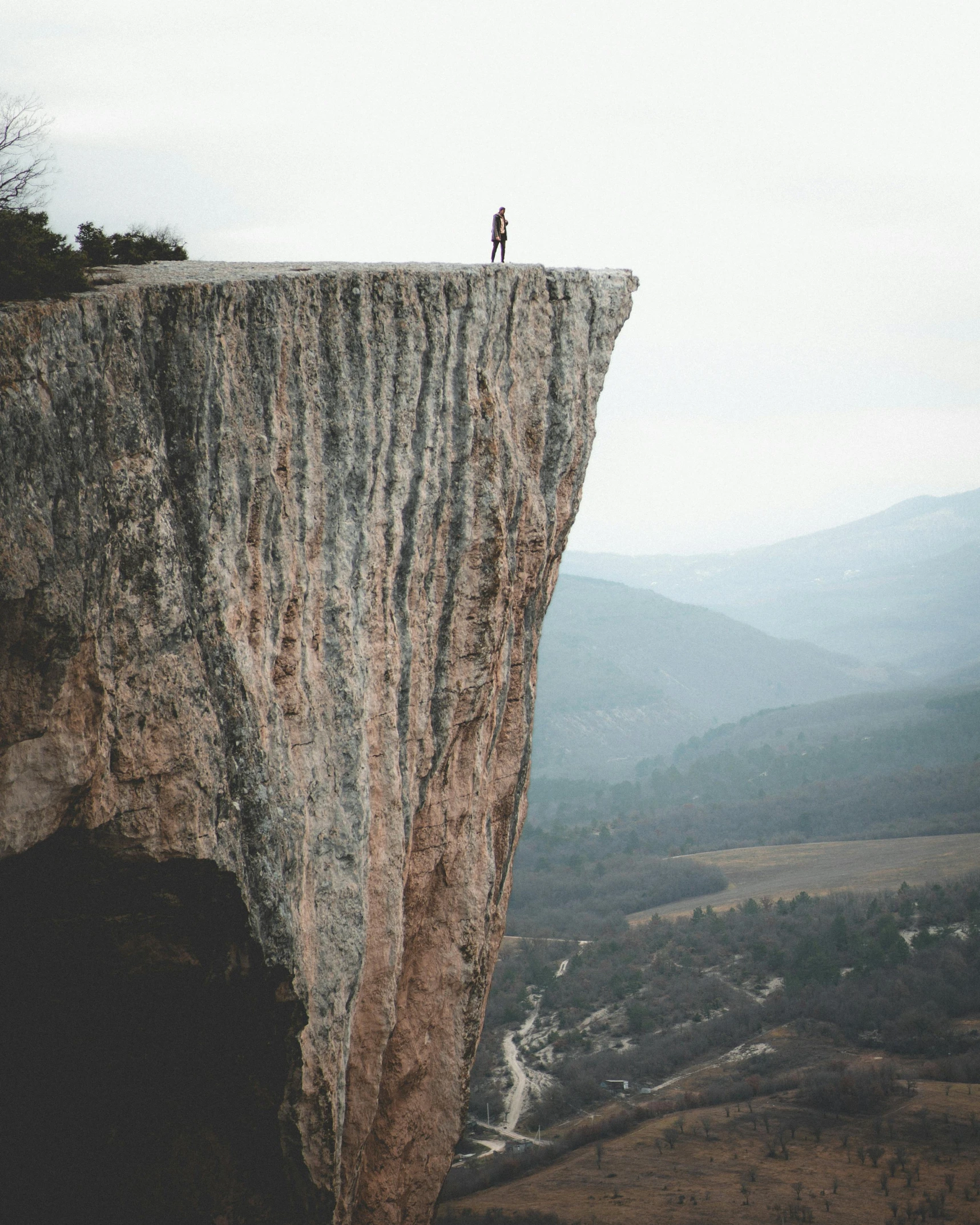 a person standing on top of a cliff, really long, grey, trending on, instagram post